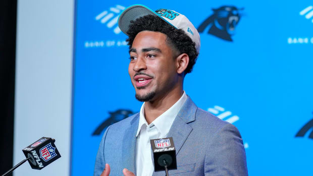 Bryce Young talks in a Panthers hat with two microphones in front of him